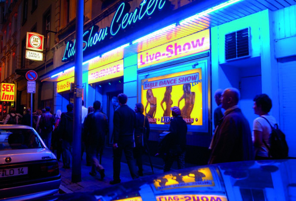 Eine Gruppe zieht nachts an einem blau beleuchteten Live-Show-Lokal im Frankfurter Bahnhofsviertel vorbei.